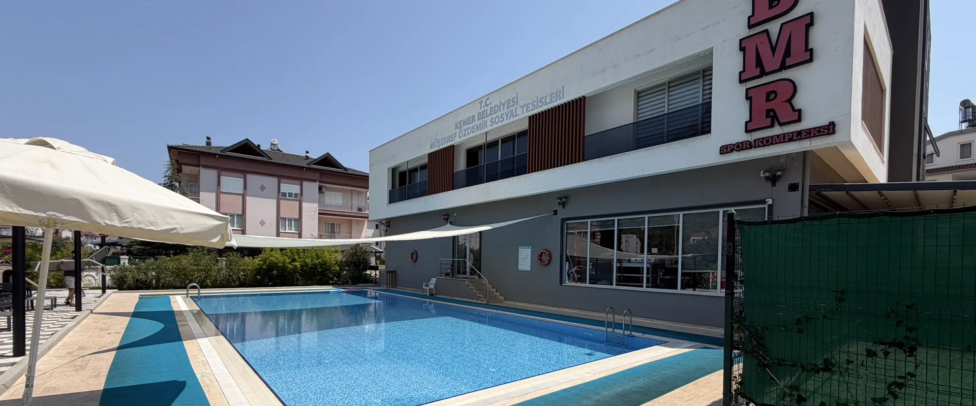 BMR Spor Kompleksi'nin dış görünümü: açık havuz, havuz kenarı ve binanın cephesindeki BMR tabelası